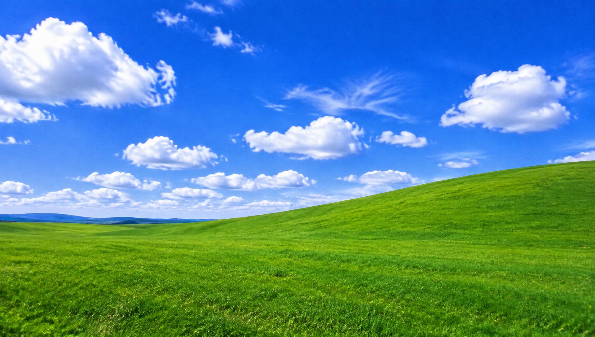 Green rolling hills under a bright blue 2000s desktop sky